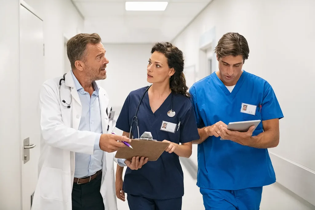 Three doctors walking together down a hospital hallway, engaged in conversation.
