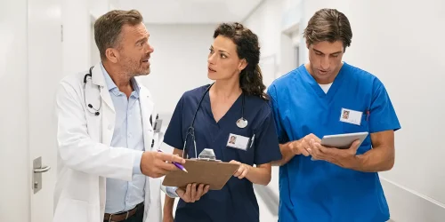 Three doctors walking together down a hospital hallway, engaged in conversation.